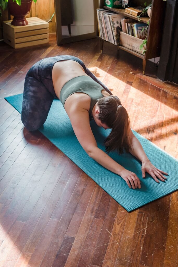 A woman stretching on a yoga mat at home in morning sunlight